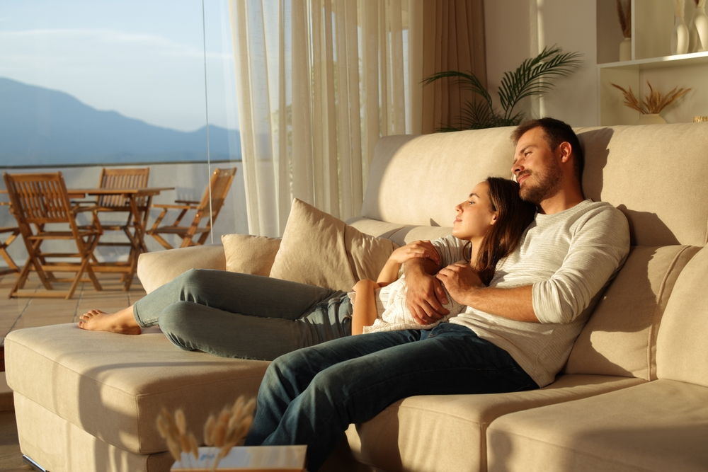 Illustration: Junges, verliebtes Paar sitzt entspannt auf der Couch und genießt den Sonnenuntergang.