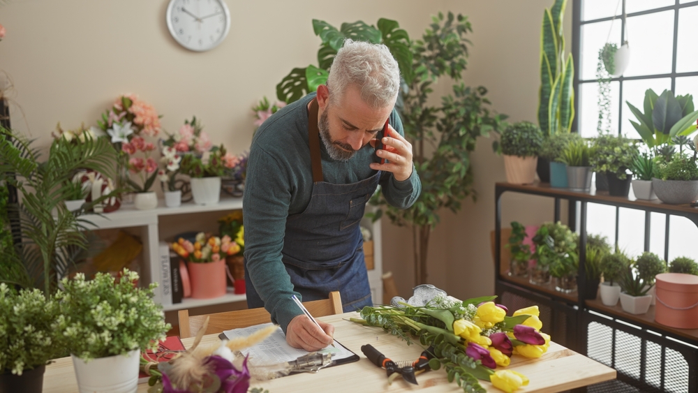 Illustration: Ein bärtiger Mann in einem Blumenladen, macht sich Notizen und telefoniert.